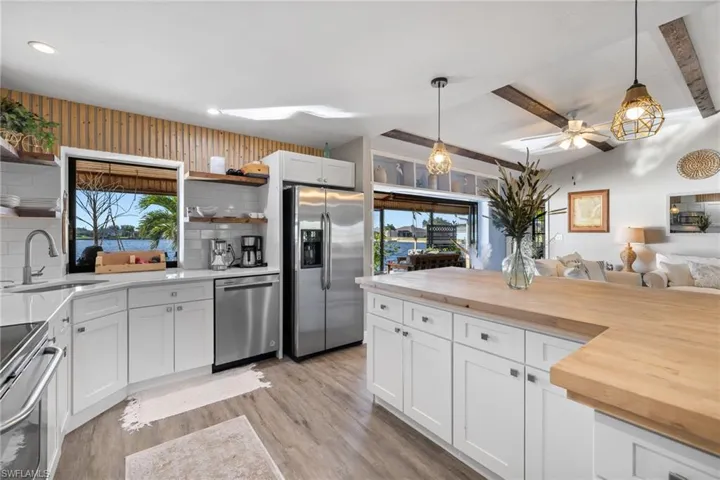 Kitchen featuring white cabinets, sink, hanging light fixtures, butcher block counters, and stainless steel appliances