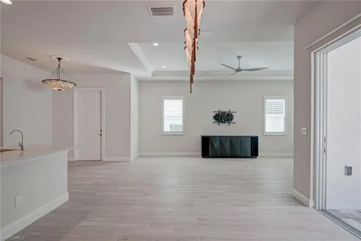 Living room with wood finish floors, a raised ceiling, recessed lighting, ceiling fan, and ornamental molding