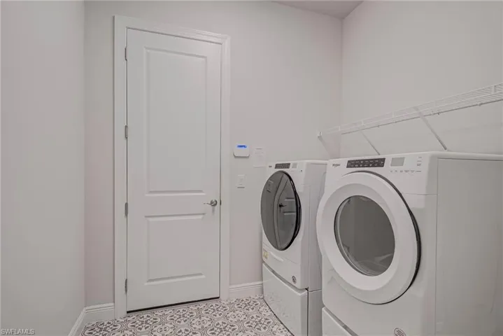 Laundry area featuring washing machine and clothes dryer and tile patterned floors