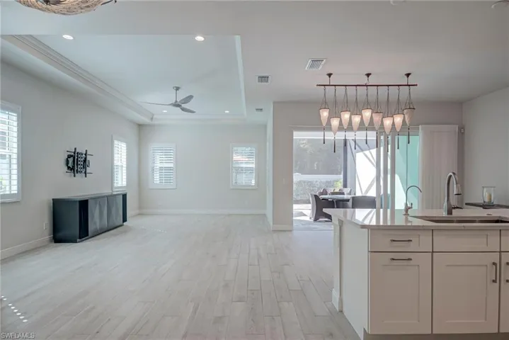 Kitchen featuring light wood-style flooring, pendant lighting, open floor plan, light stone countertops, and plenty of natural light