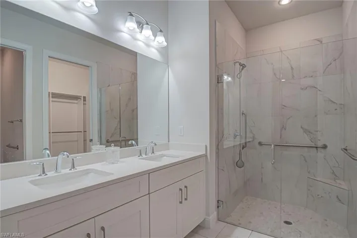 Master Bathroom with a spacious closet, double vanity, and a marble finish shower