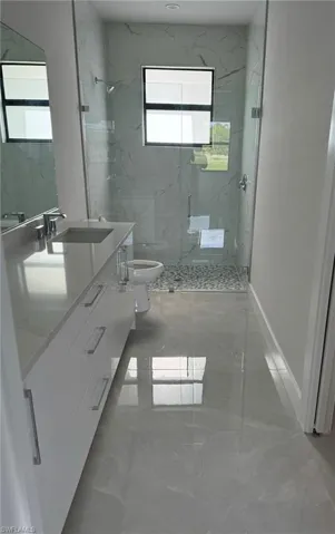 Bathroom featuring an enclosed shower, vanity, toilet, and tile patterned floors