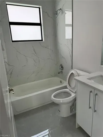 Full bathroom featuring tile patterned floors, tiled shower / bath, toilet, and vanity