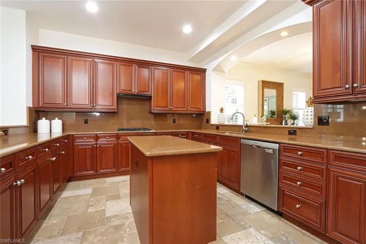Kitchen with stainless steel appliances, stone tile flooring, a center island, tasteful backsplash, and recessed lighting