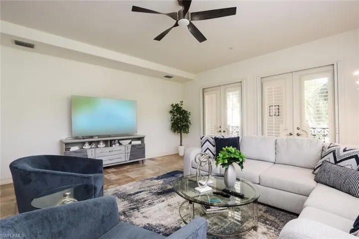 Living room featuring french doors, a ceiling fan, and stone finish flooring