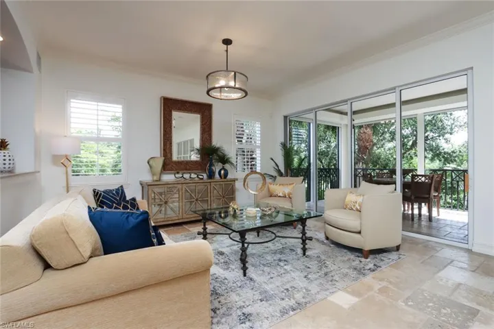 Living room featuring ornamental molding, stone tile flooring, and plenty of natural light