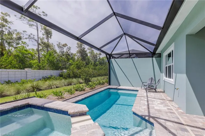 View of pool with glass enclosure, a sunroom, and a patio