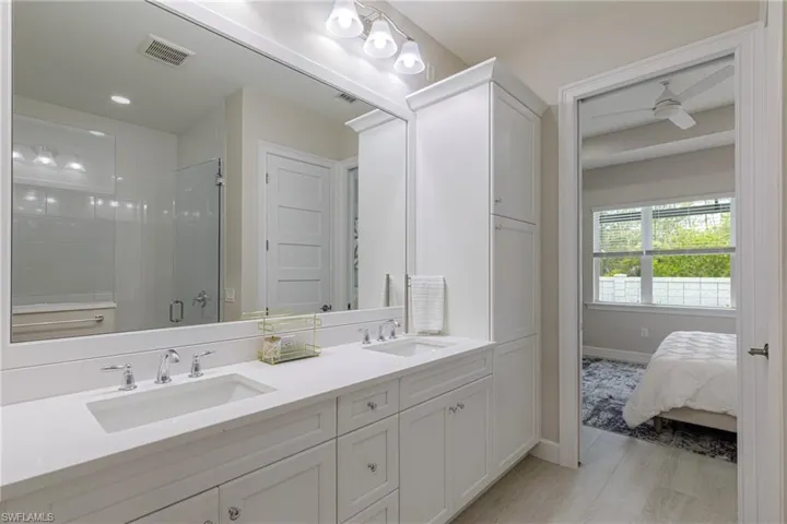 Full bathroom with a shower stall, double vanity, ceiling fan, and light wood-style flooring