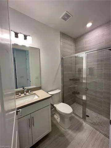 Bathroom with a stall shower, vanity, and recessed lighting