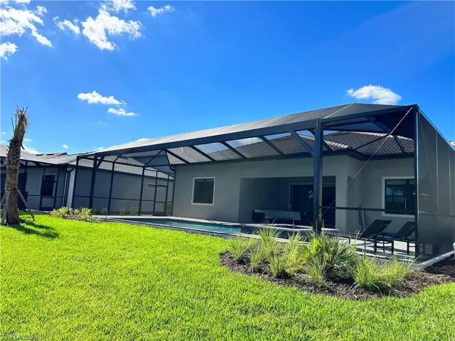 Rear view of property with a sunroom, a lanai, a lawn, an outdoor pool, and a patio area