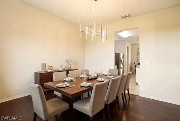 Dining area featuring dark wood-style flooring and suspended lighting