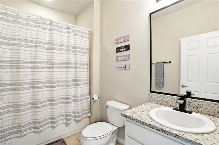 Bathroom featuring vanity, shower / bath combination with curtain, and light tile patterned floors