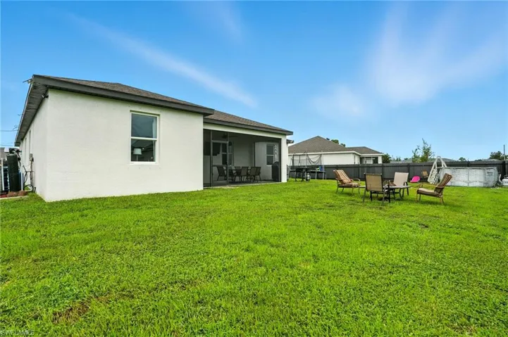Rear view of property with stucco siding, a sunroom, a pool, and roof with shingles