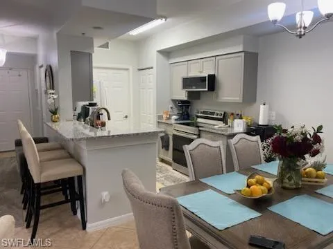 Kitchen with hanging light fixtures, appliances with stainless steel finishes, a breakfast bar, and a chandelier