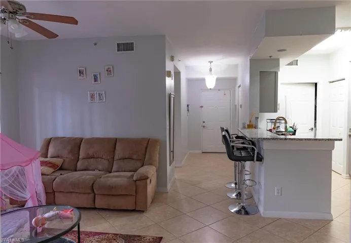 Living area with a ceiling fan and light tile patterned floors