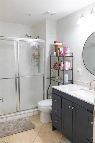 Bathroom featuring vanity, a shower stall, a textured wall, light tile patterned floors, and a textured ceiling