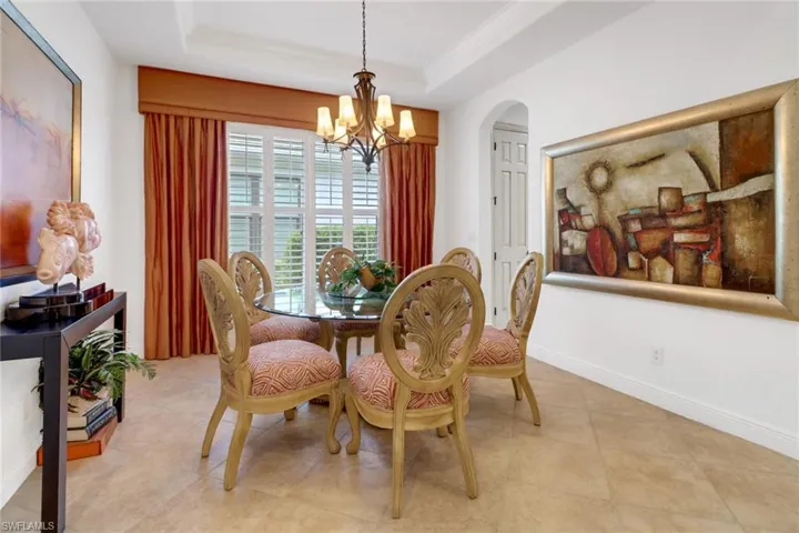 Dining space with a raised ceiling, light tile patterned flooring, and a chandelier