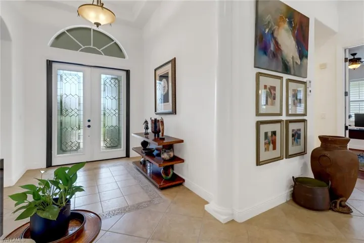 Foyer entrance featuring light tile patterned floors, a towering ceiling, french doors, and plenty of natural light