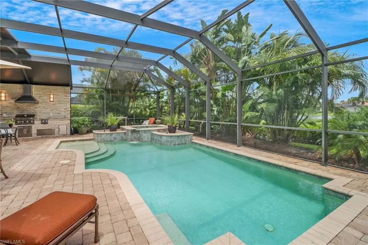 View of pool with screened enclosure, an in ground hot tub, a patio, and area for grilling