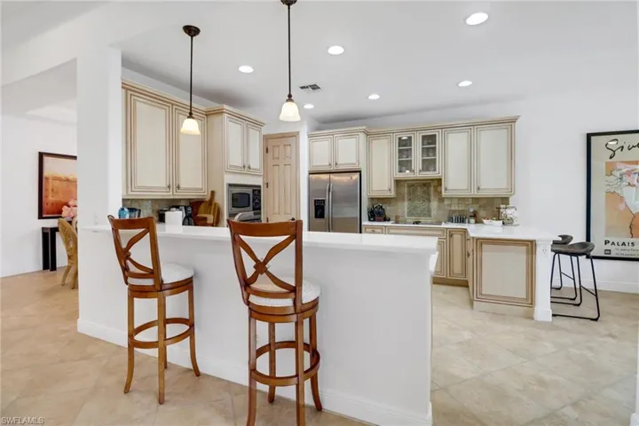 Kitchen with light tile patterned floors, hanging light fixtures, appliances with stainless steel finishes, backsplash, and cream cabinetry