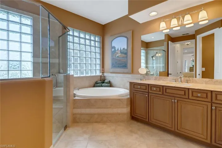 Bathroom featuring tile patterned floors, vanity, and separate shower and tub