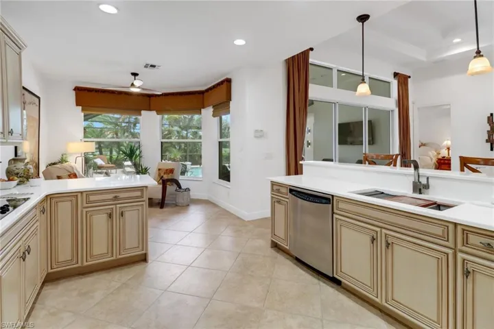Kitchen featuring hanging light fixtures, sink, light tile patterned flooring, stainless steel dishwasher, and cream cabinetry