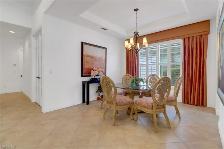 Tiled dining space with a raised ceiling and a chandelier