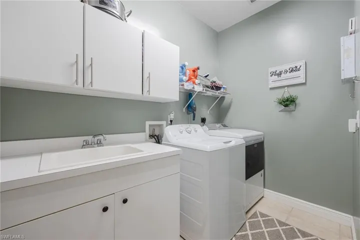 Laundry area with plenty of cabinets, hookup for your washer and dryer, a utility sink and tile floors.
