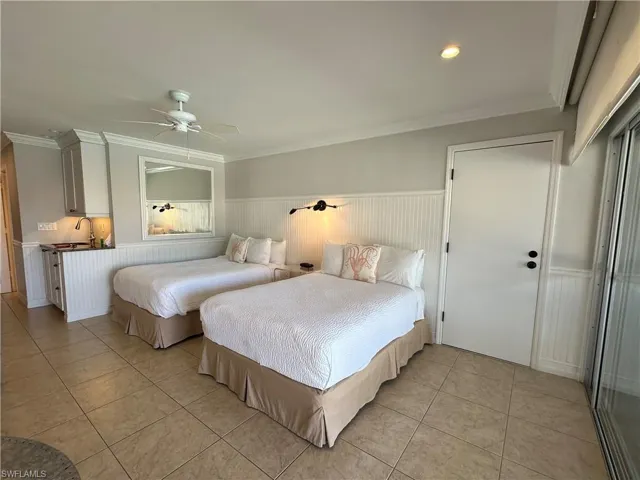 Tiled bedroom with ceiling fan, sink, and ornamental molding