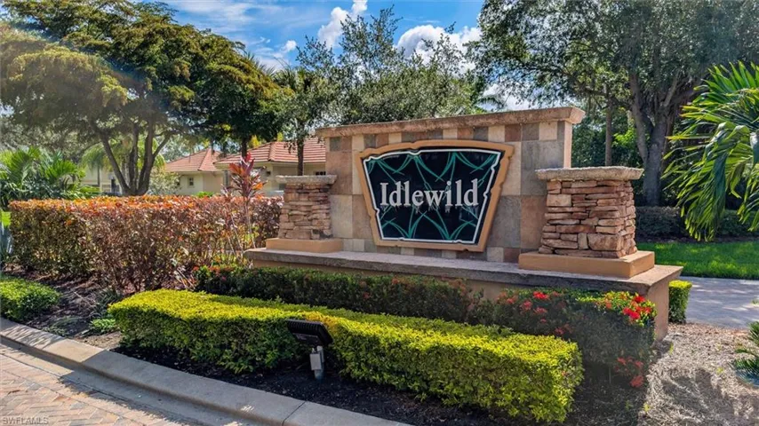 Stone and stucco community entrance sign featuring stacked stone columns and a central sign panel