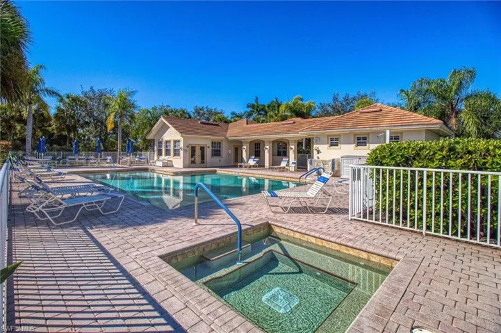 Expansive outdoor area featuring a swimming pool, integrated spa, and surrounding paver decking