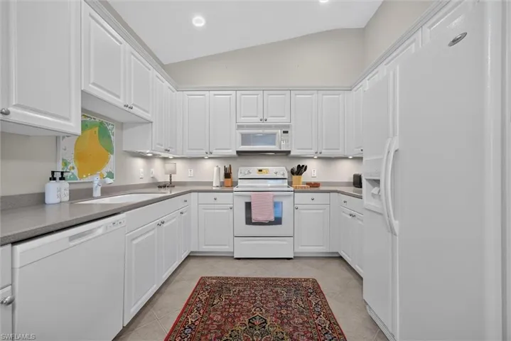 Kitchen featuring white cabinetry, gray countertops, recessed lighting, and a vaulted ceiling