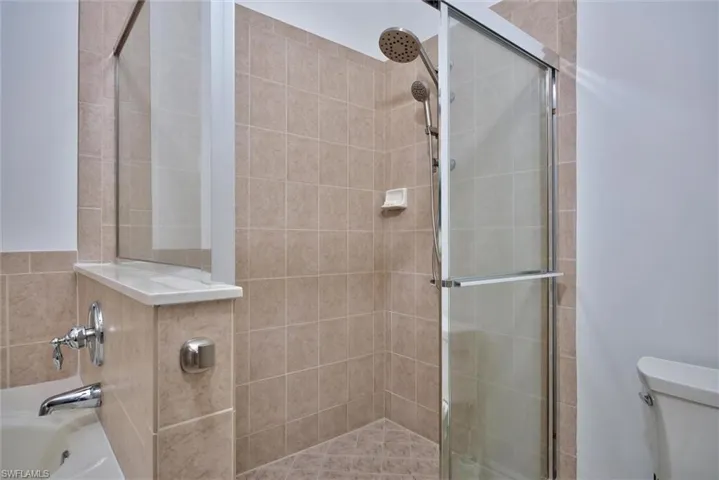 Shower with a glass enclosure, a handheld showerhead, and a fixed showerhead