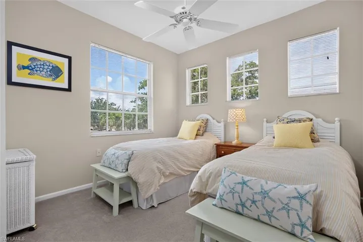 Carpeted bedroom featuring multiple windows with blinds, a white ceiling fan, and painted neutral walls