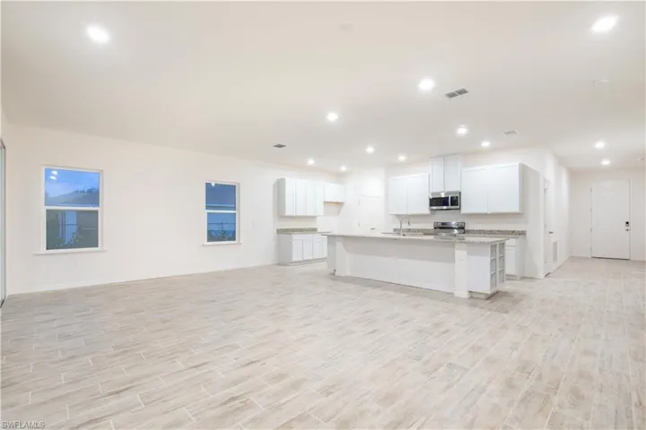 Kitchen featuring a kitchen island with sink, wood tiled floors, white cabinets, open floor plan, and recessed lighting