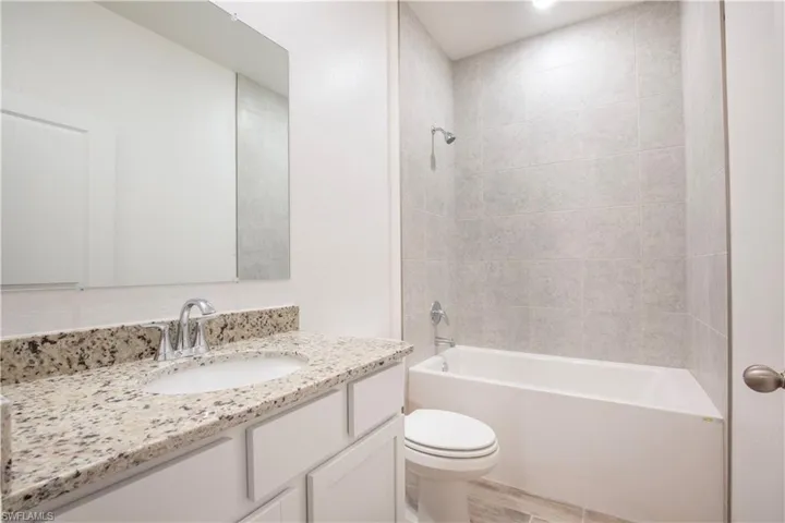 Bathroom featuring vanity, shower / bath combination, and light wood-style flooring