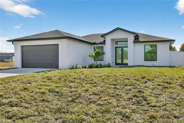 View of front facade featuring a front yard, an attached garage, stucco siding, and concrete driveway