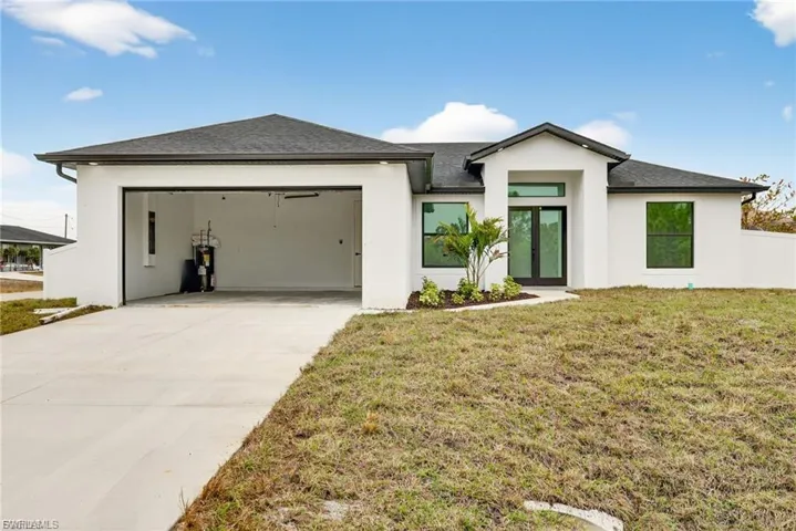 View of front of home featuring driveway, a garage, stucco siding, a front yard, and roof with shingles