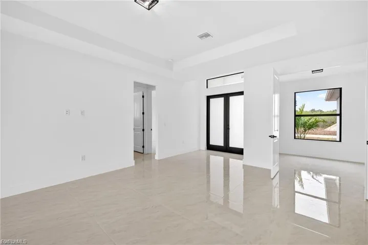 Unfurnished room featuring french doors and a tray ceiling