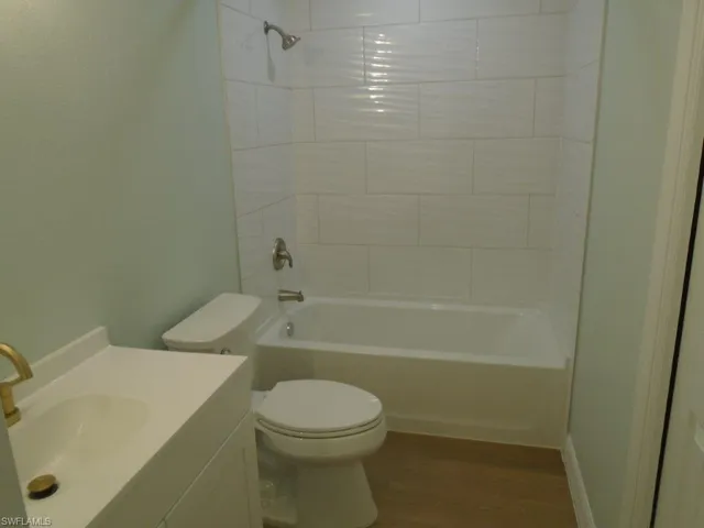 Full bathroom featuring tiled shower / bath combo, toilet, hardwood / wood-style flooring, and vanity