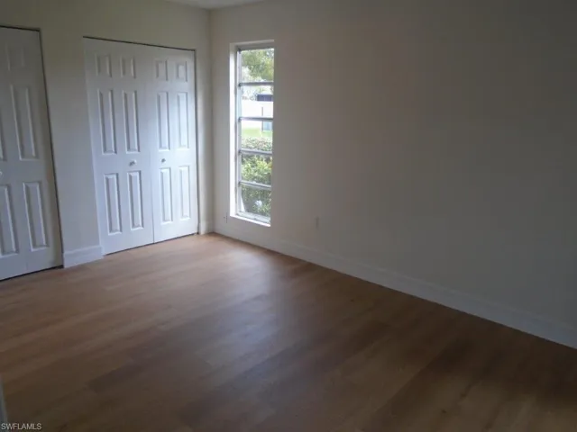 Unfurnished bedroom featuring hardwood / wood-style floors and two closets