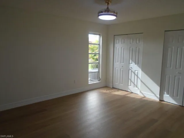 Unfurnished bedroom featuring hardwood / wood-style flooring and multiple closets