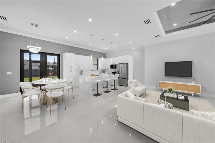 Open-concept space featuring polished tile flooring, white high-gloss cabinetry, a center island with pendant lighting, recessed ceiling lights, and a tray ceiling