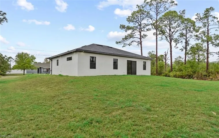 Back of house with a lawn and stucco siding