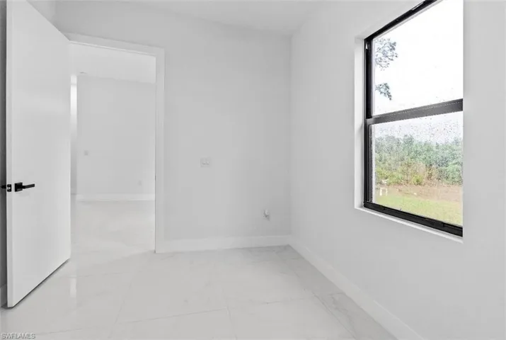 Spare room featuring baseboards and light marble finish floors