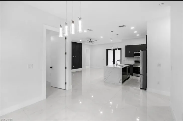 Kitchen with dark cabinetry, a ceiling fan, hanging light fixtures, and stainless steel appliances