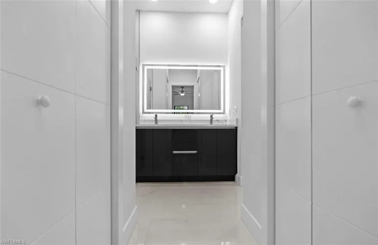 Full bathroom featuring double vanity and light marble finish floors