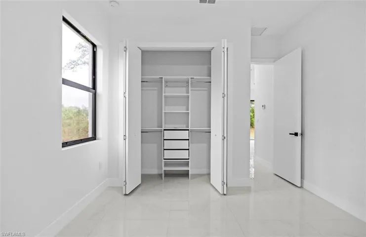 Unfurnished bedroom with multiple windows, a closet, and light marble finish flooring
