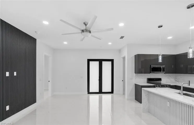 Kitchen with dark cabinetry, modern cabinets, pendant lighting, light stone counters, and black electric range oven