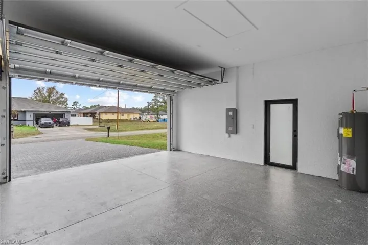 Garage with a residential view, electric water heater, and electric panel